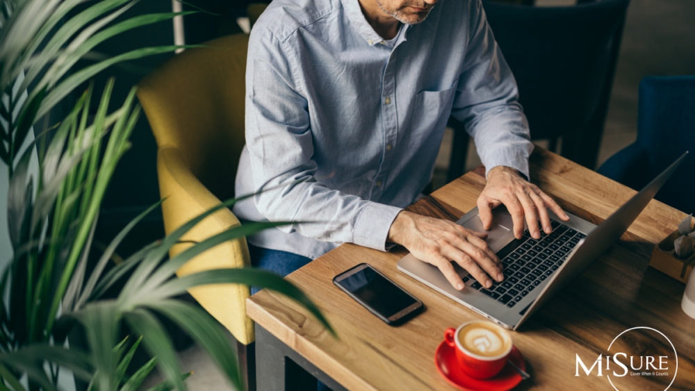 Man working with laptop at desk with red coffee cup